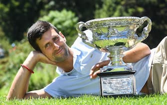 TOPSHOT - Serbia's Novak Djokovic poses for photographs with the championship trophy at the Royal Botanical Gardens in Melbourne on January 28, 2019, a day after his victory against Spain's Rafael Nadal in the men's singles final of the Australian Open tennis tournament. (Photo by William WEST / AFP) / -- IMAGE RESTRICTED TO EDITORIAL USE - STRICTLY NO COMMERCIAL USE --        (Photo credit should read WILLIAM WEST/AFP via Getty Images)