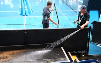 MELBOURNE, AUSTRALIA - JANUARY 23: Staff are seen attempting to clean dirt off the outside courts after being caused by rainfall on day four of the 2020 Australian Open at Melbourne Park on January 23, 2020 in Melbourne, Australia. (Photo by Mike Owen/Getty Images)