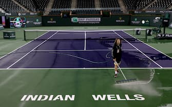 1211256595 INDIAN WELLS, CALIFORNIA - MARCH 08: Courtmaster Jeffrey Brooker cleans the center court at the Indian Wells Tennis Garden on March 08, 2020 in Indian Wells, California. The BNP Paribas Open was cancelled by the Riverside County Public Health Department, as county officials declared a public health emergency when a case of coronavirus (COVID-19) was confirmed in the area. (Photo by Matthew Stockman/Getty Images)