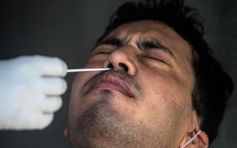 A health official collects a swab sample from a man to test for the COVID-19 coronavirus at a temporary testing center at a hotel after authorities eased restrictions imposed as a preventive measure against the spread of the COVID-19 coronavirus, in New Delhi on June 17, 2020. - India's official coronavirus death toll leapt by more than 2,000 on June 17 as the hard-hit country struggles to contain a ballooning health crisis that has overwhelmed hospitals. The news came as Germany urged its nationals in India to consider leaving for their own safety, while France warned its citizens in New Delhi to stay home unless going to an airport to return to Europe. (Photo by XAVIER GALIANA / AFP) (Photo by XAVIER GALIANA/AFP via Getty Images)