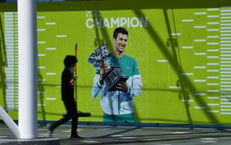epa09679555 A person walks past an image of Serbian tennis player Novak Djokovic seen on a wall at Melbourne Park in Melbourne, Australia, 12 January 2022. Djokovic, who is the number one tennis player in the world, waits to learn if his visa will be cancelled.  EPA/JAMES ROSS  AUSTRALIA AND NEW ZEALAND OUT