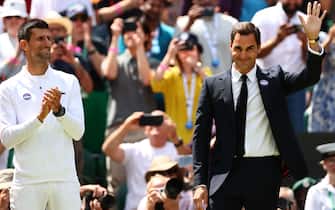 Swiss former tennis player Roger Federer (R) waves next to Serbia's Novak Djokovic as they take part in the Centre Court Centenary Ceremony, on the seventh day of the 2022 Wimbledon Championships at The All England Tennis Club in Wimbledon, southwest London, on July 3, 2022. - RESTRICTED TO EDITORIAL USE (Photo by Adrian DENNIS / AFP) / RESTRICTED TO EDITORIAL USE (Photo by ADRIAN DENNIS/AFP via Getty Images)