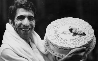 Tennis player Manuel Orantes holding up his celebration cake, in honor of his semi-final win over Mark Cox at the Dewar Cup Lawn Tennis Competition, Royal Albert Hall, London, November 5th 1976. (Photo by Keystone/Hulton Archive/Getty Images)