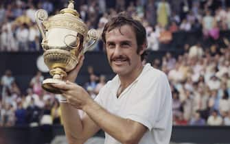 John Newcombe of Australia holds aloft the Gentlemen's Singles Championship Trophy after defeating Stan Smith of the United States, 6-3, 5-7, 2-6, 6-4, 6-4 in their Men's Singles Final match at the Wimbledon Lawn Tennis Championship on 3rd July 1971 at the All England Lawn Tennis and Croquet Club in Wimbledon, London, England. (Photo by Fox Photos/Hulton Archive/Getty Images)