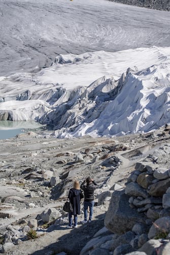 epa08553193 People visit the Rhone Glacier covered in blankets above Gletsch near the Furkapass in Switzerland, 18 July 2020. The Alps oldest glacier is protected by special white blankets to prevent it from melting.  EPA/URS FLUEELER