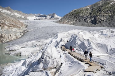 epa08553197 People visit the Rhone Glacier covered in blankets above Gletsch near the Furkapass in Switzerland, 18 July 2020. The Alps oldest glacier is protected by special white blankets to prevent it from melting.  EPA/URS FLUEELER