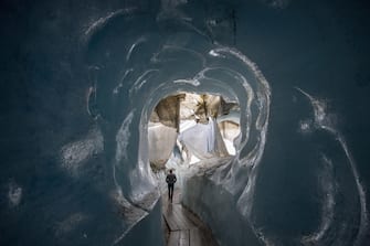 epaselect epa08553194 People visit the Ice cave in the Rhone Glacier covered in blankets above Gletsch near the Furkapass in Switzerland, 18 July 2020. The Alps oldest glacier is protected by special white blankets to prevent it from melting.  EPA/URS FLUEELER