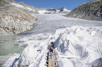 SWITZERLAND NATURE ALPS epa08553173 People visit the Rhone Glacier covered in blankets above Gletsch near the Furkapass in Switzerland, 18 July 2020. The Alps oldest glacier is protected by special white blankets to prevent it from melting. EPA/URS FLUEELER
