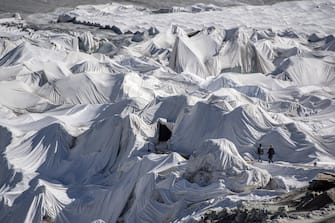 epa08553174 People visit the Rhone Glacier covered in blankets above Gletsch near the Furkapass in Switzerland, 18 July 2020. The Alps oldest glacier is protected by special white blankets to prevent it from melting.  EPA/URS FLUEELER