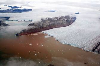 TO GO WITH AFP STORY BY CELINE SERRAT - This aerial view taken on July 20, 2015 shows the Kronebreen glacier with red traces of sediments near the scientific base of Ny Alesund.  AFP PHOTO / DOMINIQUE FAGET        (Photo credit should read DOMINIQUE FAGET/AFP via Getty Images)