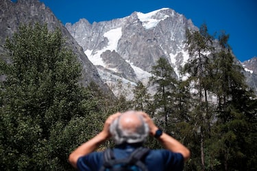 A man looks up to the Planpincieux glacier from the village of La Palud, in Courmayeur, Val Ferret, northwestern Italy, on August 6, 2020. - Several dozen people have been evacuated in northwestern Italy as a huge chunk of a glacier in the Mont Blanc massif threatens to break off due to high temperatures. (Photo by MARCO BERTORELLO / AFP) (Photo by MARCO BERTORELLO/AFP via Getty Images)