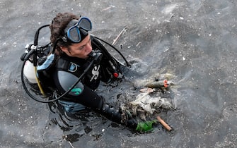 TOPSHOT - A volunteer from the Aegean Rebreath Greek organisation holds waste found in the sea at the port of the Ionian island of Zakynthos on November 23, 2019. - Within three hours a team of a dozen volunteers from Aegean Rebreath, a Greek organisation formed in 2017 to protect Aegean biodiversity from waste, collects four tyres, two shopping carts, a street lamp, metal boxes, plastic bags, dozens of plastic bottles and several kilometres of fishing line. In its two years of operation, Aegean Rebreath has amassed 9,000 plastic water bottles, 3,6 tons of fishing net and 289 tyres. The Mediterranean, a partly closed sea, accumulates 570,000 tons of plastic annually from surrounding countries, according to the World Wildlife Fund. (Photo by LOUISA GOULIAMAKI / AFP) (Photo by LOUISA GOULIAMAKI/AFP via Getty Images)