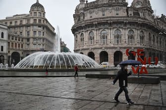 People wearing a protection mask walk across Piazza Raffaele de Ferrari in Genoa, Liguria, on March 13, 2020 as Italy shut all stores except for pharmacies and food shops in a desperate bid to halt the spread of a coronavirus. (Photo by Marco BERTORELLO / AFP) (Photo by MARCO BERTORELLO/AFP via Getty Images)