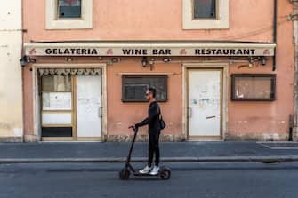 ROME, ITALY - SEPTEMBER 17:  A man passes a closed shop on Via del Corso on a scooter in the town centre on September 17, 2020 in Rome, Italy. With the COVID-19 pandemic and the almost total absence of foreign tourism, many shops and hotels will no longer reopen. (Photo by Stefano Montesi - Corbis/ Getty Images)