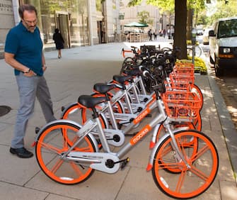 A man looks over  Mobikes on the streets of Washington, DC, on September 20, 2017, after about 200 of the bicycles that are rented via an app that finds the closest bicycle via GPS became available for public use. - Chinese bike-sharing giant Mobike on Wednesday launched in the US capital, bringing its "dockless" system which has swept China and is used in some 180 cities worldwide. (Photo by Paul J. RICHARDS / AFP)        (Photo credit should read PAUL J. RICHARDS/AFP via Getty Images)