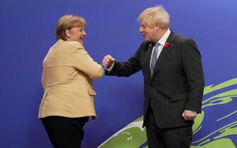 Britain's Prime Minister Boris Johnson greets Germany's Chancellor Angela Merkel as they arrive to attend the COP26 UN Climate Change Conference in Glasgow, Scotland on November 1, 2021. - COP26, running from October 31 to November 12 in Glasgow will be the biggest climate conference since the 2015 Paris summit and is seen as crucial in setting worldwide emission targets to slow global warming, as well as firming up other key commitments. (Photo by Christopher Furlong / POOL / AFP) (Photo by CHRISTOPHER FURLONG/POOL/AFP via Getty Images)