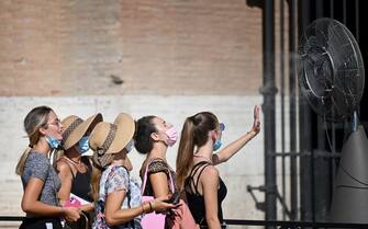 TOPSHOT - A group of woman cool off in front of a cooling fan during a heatwave as they queue at the enterance of the Colosseum in Rome on August 12, 2021. - An anticyclone dubbed Lucifer is sweeping across Italy, sending temperatures soaring and causing what is believed to be a new European record of 48.8 degrees Celsius (119.8 Fahrenheit) in Sicily on August 11. (Photo by Alberto PIZZOLI / AFP) (Photo by ALBERTO PIZZOLI/AFP via Getty Images)