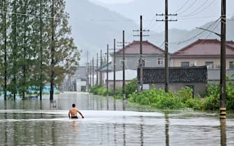 TOPSHOT - A man walks down a flooded area in Yuyao near the city of Ningbo in eastern China's Zhejiang province on July 26, 2021, after heavy rains brought by the passage of Typhoon In-Fa inundated the eastern coast of China. (Photo by HECTOR RETAMAL / AFP) (Photo by HECTOR RETAMAL/AFP via Getty Images)