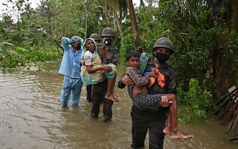 TOPSHOT - Indian army personnel wades through the flooded village roads carrying people to safety as Cyclone Yaas barrels towards India's eastern coast in the Bay of Bengal, in Ramnagar some 180 Kms from Kolkata on May 26, 2021. (Photo by Dibyangshu SARKAR / AFP) (Photo by DIBYANGSHU SARKAR/AFP via Getty Images)