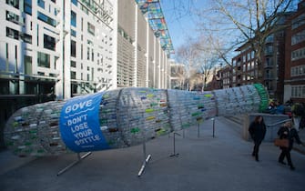 Greenpeace activists, carrying a 29 foot-long plastic bottle artwork, at the Department for Environment, Food and Rural Affairs at the Home Office in London, to deliver the bottle to Environment Secretary Michael Gove, to urge him not to 'lose his bottle' in the face of corporate lobbying, and to press on with an all-inclusive deposit return scheme.