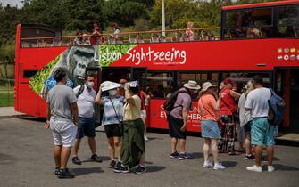 Tourists shelter from the sun as they wait to board a city sightseeing bus during a heatwave in the Marques de Pombal district of Lisbon, Portugal, on Wednesday, July 13, 2022. Temperatures are soaring across Europe, drying up waterways and boosting demand for electricity to cool homes as the region faces a crunch for energy supplies. Photographer: Goncalo Fonseca/Bloomberg