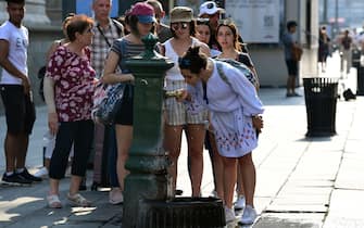 People queue to drink water from a public tap near the Duomo Cathedral, in Milan on June 28, 2019, during a heatwave. - Meteorologists blamed a blast of torrid air from the Sahara for the unusually early summer heatwave, which could send thermometers up to 40 degrees Celsius (104 Fahrenheit) in some places on June 27 and 28. Experts say such heatwaves early in the summer are likely to be more frequent as the planet heats up. (Photo by Miguel MEDINA / AFP)        (Photo credit should read MIGUEL MEDINA/AFP via Getty Images)