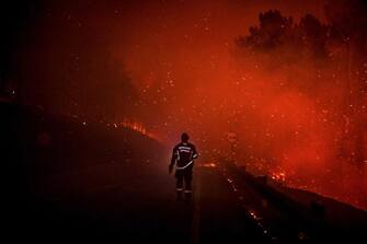 TOPSHOT - A firefighter walks on the road with a flash light during a wildfire in Manteigas, central Portugal, on August 10, 2022. - A wildfire that broke out on August 6 has been raging in the natural park of Serra da Estrela. (Photo by PATRICIA DE MELO MOREIRA / AFP) (Photo by PATRICIA DE MELO MOREIRA/AFP via Getty Images)