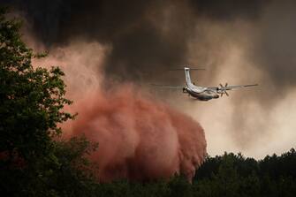 TOPSHOT - A firefighting aircraft sprays fire retardant over trees during a wildfire near Saint-Magne, southwestern France, on August 11, 2022. (Photo by Philippe LOPEZ / AFP) (Photo by PHILIPPE LOPEZ/AFP via Getty Images)