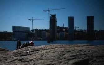 A man enjoys the warm spring weather as he relaxes by the water at Tanto in Sodermalm, Stockholm on April 21, 2020, during the new coronavirus COVID-19 pandemic. (Photo by Jonathan NACKSTRAND / AFP) (Photo by JONATHAN NACKSTRAND/AFP via Getty Images)