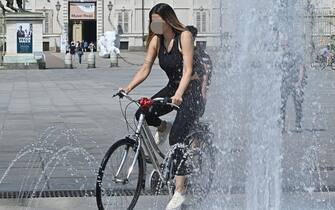 Persone cercano refigerio nelle fontane e nei giardini per il caldo torrido e fiume po in secca a Torino, 16 giugno 2022 ANSA/ALESSANDRO DI MARCO