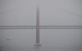 The “25th of April” suspension bridge, an iconic view of Lisbon, in the midst of the fog