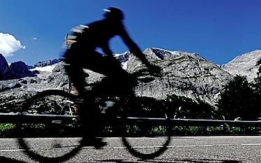 A cyclist passes in front of the Punta Rocca glacier that collapsed near Canazei, on the mountain of Marmolada, after a record-high temperature of 10 degrees Celsius (50 degrees Fahrenheit) was recorded at the glacier's summit, on July 6, 2022. - The deadly collapse of an Italian glacier, causing an avalanche which killed at least seven people, is linked to climate change, Italy's Prime Minister Mario Draghi said on July 5, 2022. (Photo by Tiziana FABI / AFP) (Photo by TIZIANA FABI/AFP via Getty Images)