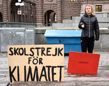 epa10299301 wedish climate activist Greta Thunberg stands next to a placard (L) reading 'school strike for climate' during the weekly Fridays for Future demonstration, at Mynttorget square near the Swedish Parliament in Stockholm, Sweden, 11 November 2022.  EPA/PONTUS LUNDAH  SWEDEN OUT
