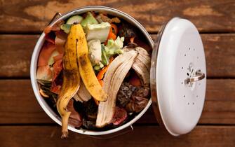 Overhead view of fruit and vegetable scraps in a white enamel container, ready to go in the compost.