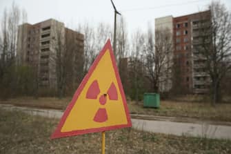 PRIPYAT, UKRAINE - APRIL 09:  A sign warns of radiation contamination near former apartment buildings on April 9, 2016 in Pripyat, Ukraine. Pripyat, built in the 1970s as a model Soviet city to house the workers and families of the Chernobyl nuclear power plant, now stands abandoned inside the Chernobyl Exclusion Zone, a restricted zone contaminated by radiation from the 1986 meltdown of reactor number four at the nearby Chernobyl plant in the world's worst civilian nuclear accident that spewed radiaoactive fallout across the globe. Authorities evacuated approximately 43,000 people from Pripyat in the days following the disaster and the city, with its high-rise apartment buildings, hospital, shops, schools, restaurants, cultural center and sports facilities, has remained a ghost-town ever since. The world will soon commemorate the 30th anniversary of the April 26, 1986 Chernobyl disaster. Today tour operators bring tourists in small groups to explore certain portions of the exclusion zone.  (Photo by Sean Gallup/Getty Images)