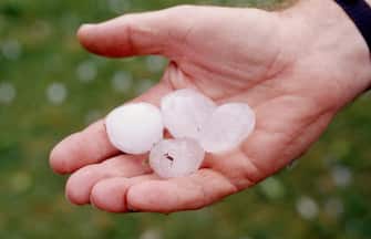 MANS HAND HOLDING LARGE HAIL STONES FROM RECENT STORMS, NEW SOUTH WALES, AUSTRALIA.