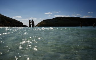 Tourists bathe on the beach of the Isola dei Conigli (Rabbit Island) in Lampedusa on September 27, 2018. - Five years after the worst shipwreck of its history, the Italian Pelagie island of Lampedusa relies on the flood of tourists to make a fresh start, though it might become a gateway to Europe again. (Photo by Alberto PIZZOLI / AFP) / TO GO WITH AFP STORY BY FANNY CARRIER        (Photo credit should read ALBERTO PIZZOLI/AFP via Getty Images)