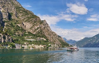 1034264458 LIMONE, ITALY - JUNE 29: View of the city, mountains and a tourist ship from a ferry boat at the northern part of the Lake Garda on June 29, 2018 in Limone, Italy. (Photo by EyesWideOpen/Getty Images)