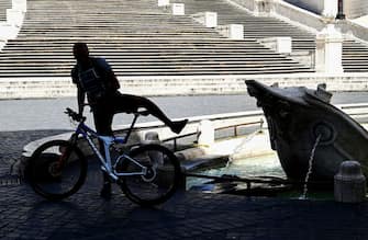 A man gets on his bicycle by the Fontana della Barcaccia at the bottom of the Spanish Steps in central Rome on May 8, 2020, during the country's lockdown aimed at curbing the spread of the COVID-19 infection, caused by the novel coronavirus. (Photo by Vincenzo PINTO / AFP) (Photo by VINCENZO PINTO/AFP via Getty Images)