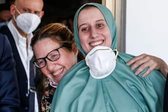 La cooperante Silvia Romano, vestita con una tunica verde, abbracciata dalla madre Francesca Fumagalli al suo arrivo all'aeroporto di Caimpino, Roma. 10 maggio 2020. ANSA / FABIO FRUSTACI