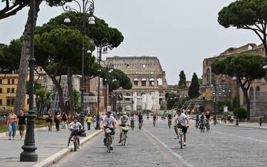 People ride their bicycles along the Fori Imperiali street in central Rome on May 17, 2020 during the country's lockdown aimed at curbing the spread of the COVID-19 infection, caused by the novel coronavirus. (Photo by Andreas SOLARO / AFP) (Photo by ANDREAS SOLARO/AFP via Getty Images)