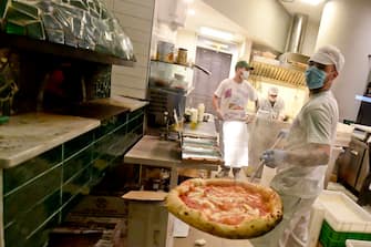 Super lavoro in una delle pizzerie aperte a Napoli dopo la chiusura imposta da Coronavirus. Secondo  Antonio Pace, presidente dell'associazione Verace Pizza Napoletana, sono circa sessantamila quelle sfornate stasera in citta' , 27 aprile 2020 
ANSA /CIRO FUSCO