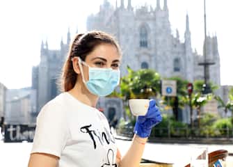 Una ragazza prende un caff èin piazza del Duomo a Milano, 18 maggio 2020.
ANSA / MATTEO BAZZI