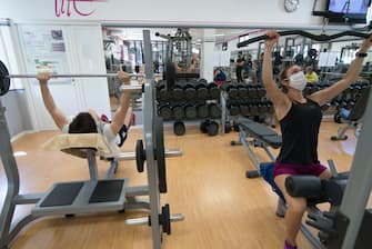 TURIN, ITALY - MAY 25: (L-R) Man wears protective mask and a Woman wears protective mask while training remotely inside a gym on May 25, 2020 in Turin, Italy. The Italian government is reopening gyms, swimming pools and sports centers for physical training activities within social distancing rules. Many Italian businesses have been allowed to reopen, after more than two months of a nationwide lockdown meant to curb the spread of Covid-19. (Photo by Stefano Guidi/Getty Images)