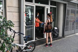 Arianna Sisto (L), owner of the "Crossfit Trastevere" gym in the Trastevere district of Rome, hands plastic shoe covers to a customer on May 25, 2020 in Rome, as the country eases its lockdown aimed at curbing the spread of the COVID-19 infection, caused by the novel coronavirus. - Swimming pools, gyms and fitness clubs reopened in Italy on May 25, 2020, marking a new stage in the deconfinement that begun three weeks ago. (Photo by ANDREAS SOLARO / AFP) (Photo by ANDREAS SOLARO/AFP via Getty Images)