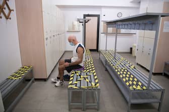 TURIN, ITALY - MAY 25: Man wears protective mask while changing clothes after training inside the locker room with with the symbols of social distance inside a gym on May 25, 2020 in Turin, Italy. The Italian government is reopening gyms, swimming pools and sports centers for physical training activities within social distancing rules. Many Italian businesses have been allowed to reopen, after more than two months of a nationwide lockdown meant to curb the spread of Covid-19. (Photo by Stefano Guidi/Getty Images)