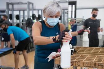 TURIN, ITALY - MAY 25: Woman wears protective mask while cleaning training tools with a disinfectant spray after training inside a gym on May 25, 2020 in Turin, Italy. The Italian government is reopening gyms, swimming pools and sports centers for physical training activities within social distancing rules. Many Italian businesses have been allowed to reopen, after more than two months of a nationwide lockdown meant to curb the spread of Covid-19. (Photo by Stefano Guidi/Getty Images)