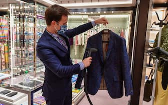 A seller steam sanitizes a jacket for a customer to try on at an Etro fashion shop on May 18, 2020 in Milan during the country's lockdown aimed at curbing the spread of the COVID-19 infection, caused by the novel coronavirus. - Restaurants and churches reopen in Italy on May 18, 2020 as part of a fresh wave of lockdown easing in Europe and the country's latest step in a cautious, gradual return to normality, allowing businesses and churches to reopen after a two-month lockdown. (Photo by Miguel MEDINA / AFP) (Photo by MIGUEL MEDINA/AFP via Getty Images)