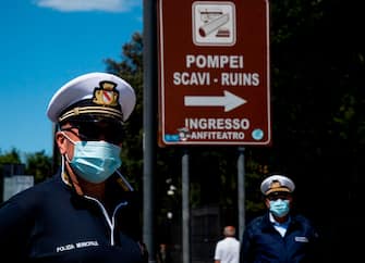Municipal police officers stand guard at the entrance of the archeological site of Pompeii on May 26, 2020, as the country eases its lockdown aimed at curbing the spread of the COVID-19 infection, caused by the novel coronavirus. - Italy's world-famous archeological site Pompeii reopened to the public on May 26,bBut with foreign tourists still prohibited from travel to Italy until June, the site that attracted just under 4 million visitors in 2019 is hoping that for now, Italian tourists can make up at least a fraction of the difference. (Photo by Tiziana FABI / AFP) (Photo by TIZIANA FABI/AFP via Getty Images)