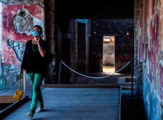 A visitor wearing a face mask walks across the archeological site of Pompeii on May 26, 2020, as the country eases its lockdown aimed at curbing the spread of the COVID-19 infection, caused by the novel coronavirus. - Italy's world-famous archeological site Pompeii reopened to the public on May 26,bBut with foreign tourists still prohibited from travel to Italy until June, the site that attracted just under 4 million visitors in 2019 is hoping that for now, Italian tourists can make up at least a fraction of the difference. (Photo by Tiziana FABI / AFP) (Photo by TIZIANA FABI/AFP via Getty Images)